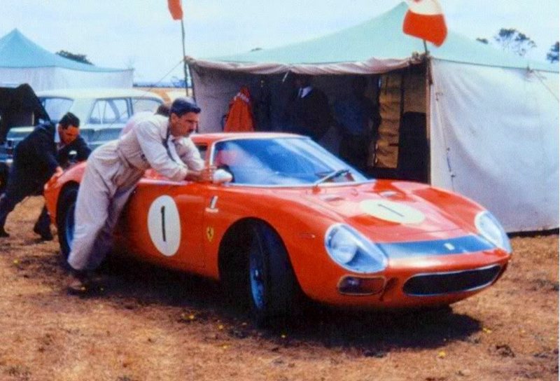 A red Ferrari 250 LM, race number 1, in the paddock beside a marquee