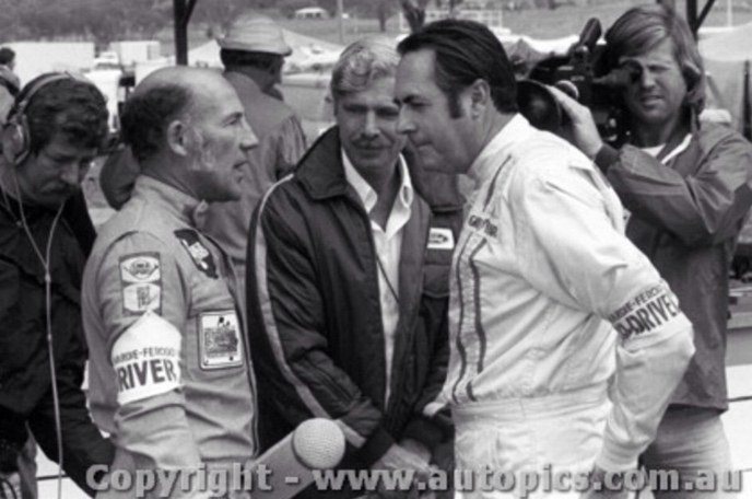 David McKay in conversation with fellow drivers in racing overalls