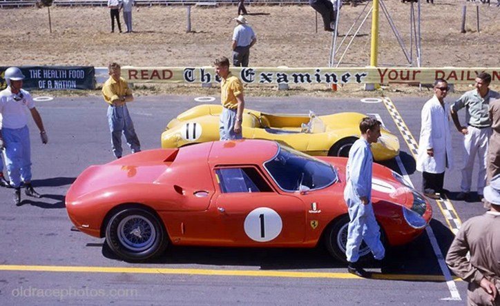 Race cars on the grid at a street circuit, spectators behind a newspaper hoarding