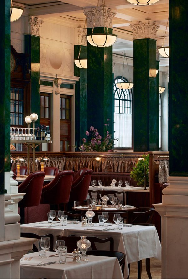 A brasserie dining room with green columns and white linen